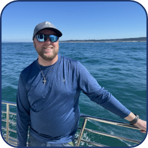 Person in blue shirt and sunglasses on boat with ocean view.
